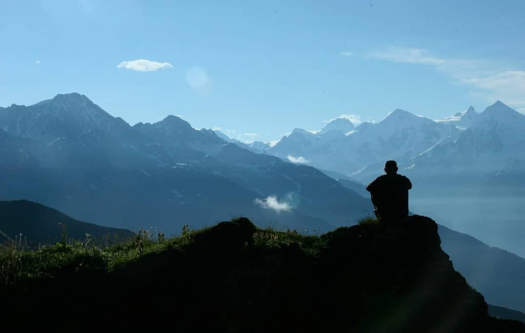 człowiek na szczyćie góry, patrzący na szczyty gór